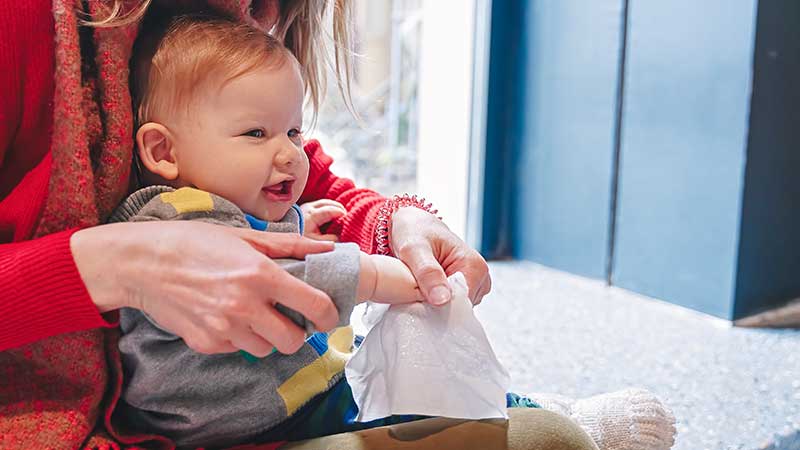 Mulher com um bebé ao colo e ambos a pegar numa toalhita
